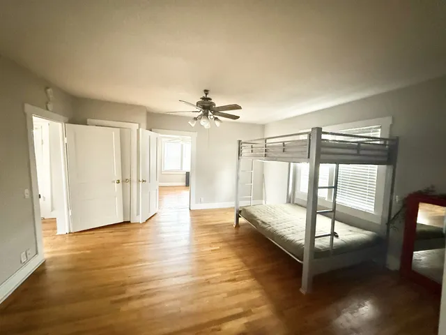 a view of an empty room with window and wooden floor