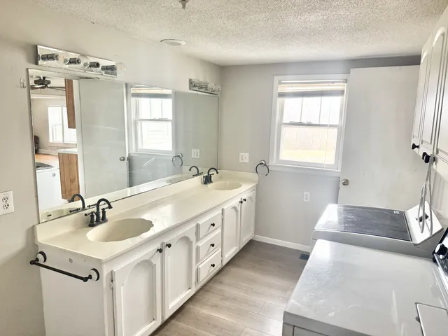 a spacious bathroom with double vanity sink a mirror a window and a shower