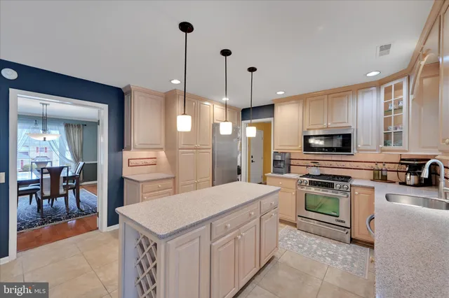 a kitchen with a refrigerator a oven a sink a dining table and chairs with wooden floor