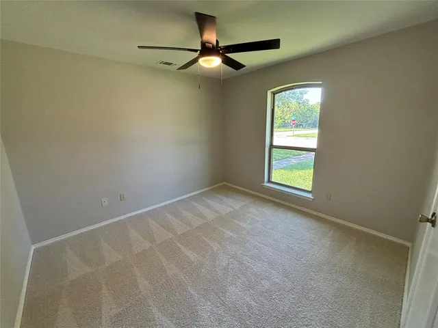 an empty room with a window and a fan