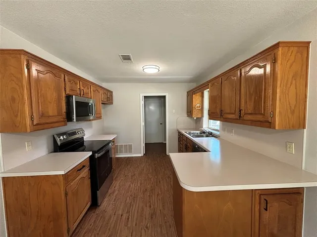 a kitchen with stainless steel appliances a sink wooden floor cabinets and a refrigerator