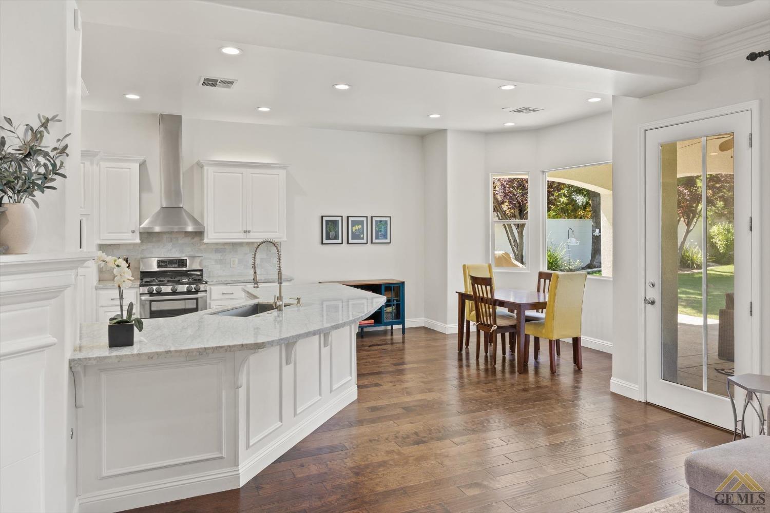 Undisclosed Address Bakersfield, CA 93311 - Photo 17 of 45 a kitchen with stainless steel appliances granite countertop a stove top oven a sink a dining table and chairs with wooden floor