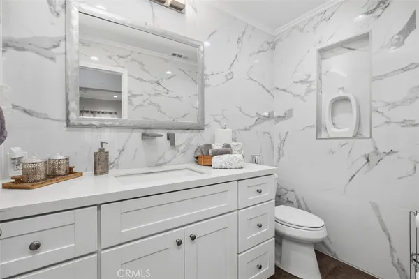 a bathroom with a granite countertop sink a toilet and mirror