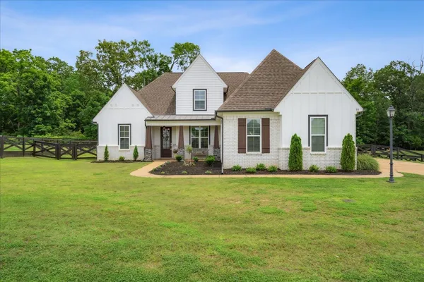 a front view of a house with a yard and trees