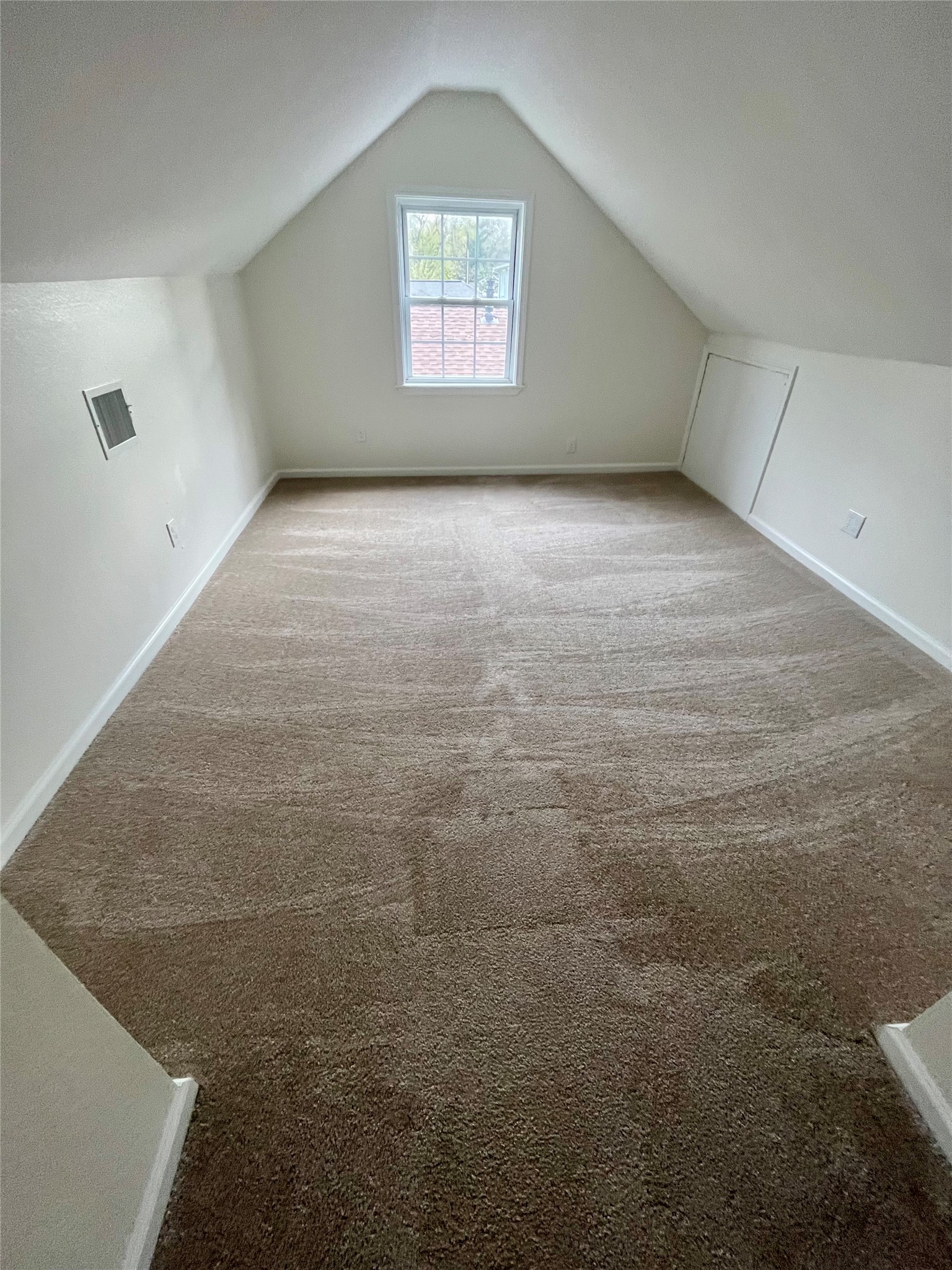 302 Moody Street Houston, TX 77009 - Photo 9 of 11 The upstairs gameroom features a cozy, carpeted space with sloped ceilings and a single window, offering natural light. Ideal for a small office or storage.