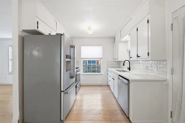 a kitchen with a sink a counter top space stainless steel appliances cabinets and a window
