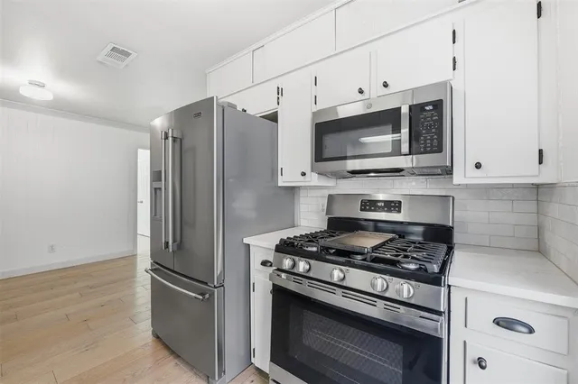 a kitchen with stainless steel appliances white cabinets and stove