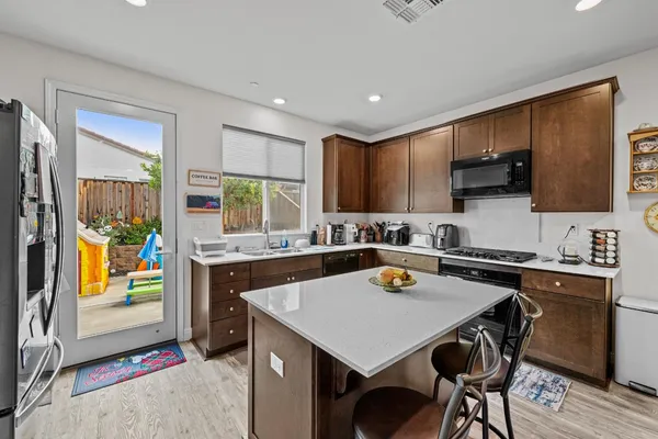 a kitchen with a sink a stove and chairs with wooden floor