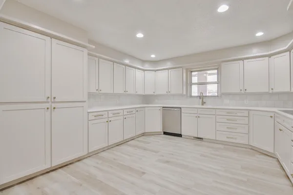 a kitchen with white cabinets white appliances and window