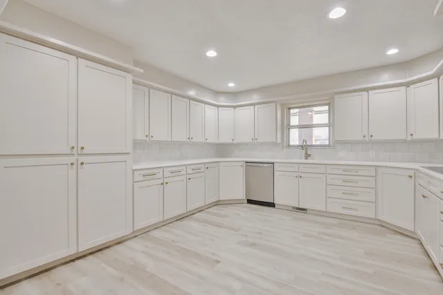 a kitchen with white cabinets white appliances and window