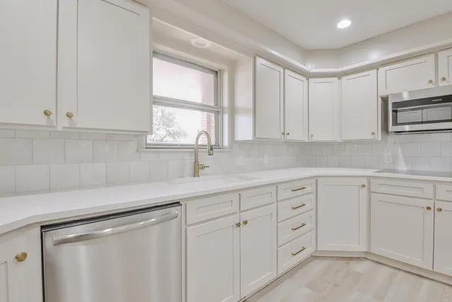 a kitchen with white cabinets and sink