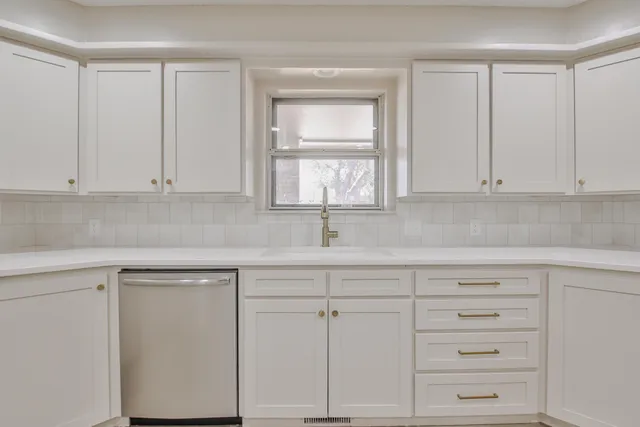 a kitchen with white cabinets and a window