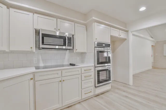 a kitchen with white cabinets and stainless steel appliances