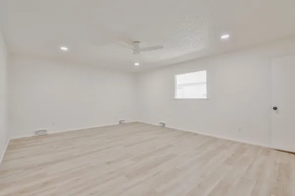 an empty room with a window and a ceiling fan