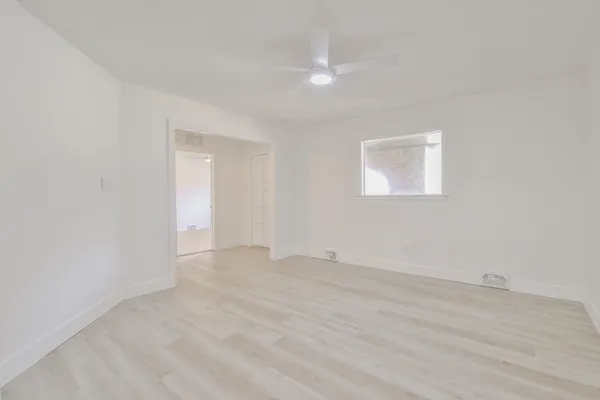 a view of an empty room with wooden floor and a window