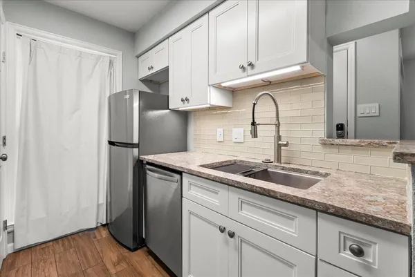 a kitchen with granite countertop a sink stainless steel appliances and cabinets