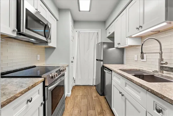 a kitchen with granite countertop cabinets stainless steel appliances and wooden floor