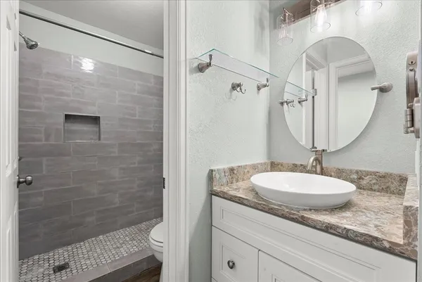 a bathroom with a granite countertop sink a mirror and shower