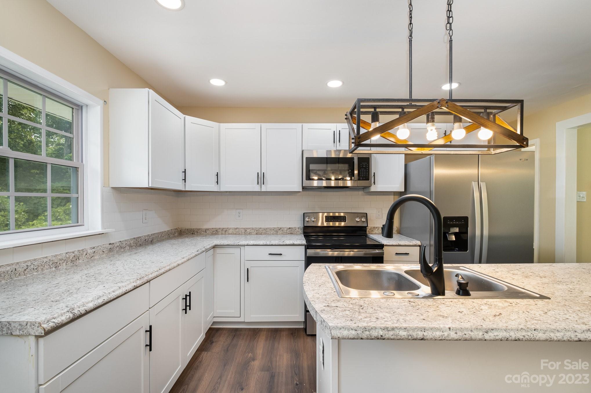 260 Upper Stanley Road Stanley, NC 28164 - Photo 8 of 18 a kitchen with kitchen island granite countertop a stove a sink and a granite counter tops with white cabinets