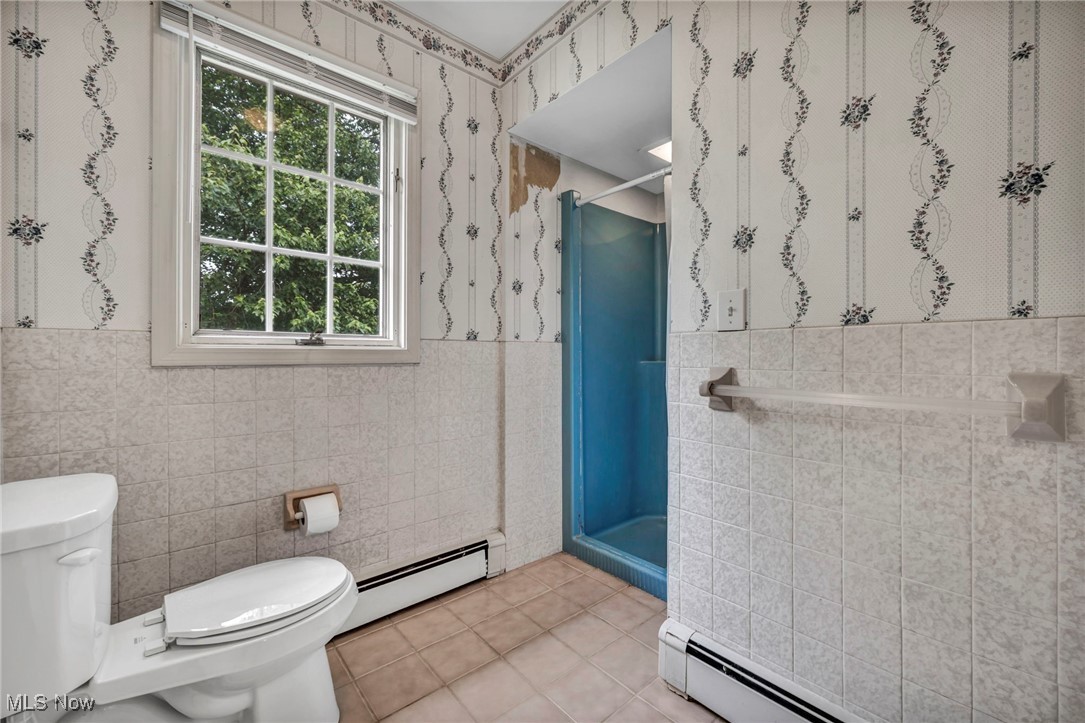 38814 Johnnycake Ridge Road Willoughby, OH 44094 - Photo 23 of 48 Bathroom featuring baseboard heating, tile walls, toilet, a stall shower, and tile patterned floors