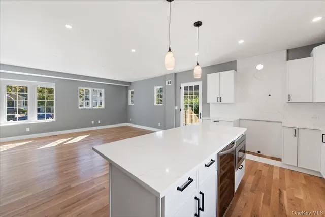 a kitchen with stainless steel appliances granite countertop a refrigerator a sink dishwasher a stove and white countertops with wooden floor