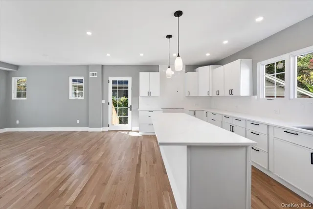 a large kitchen with stainless steel appliances kitchen island a large counter top a sink and a chandelier