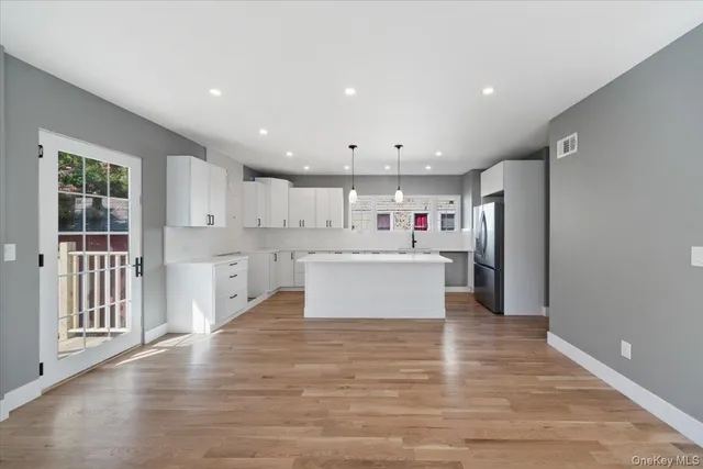 a large white kitchen with kitchen island a stove a sink dishwasher and a large countertops with wooden floor