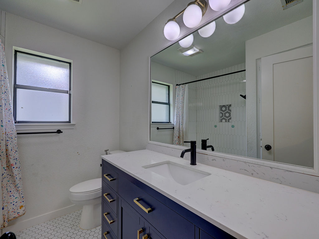 5842 Secrest Drive Austin, TX 78759 - Photo 27 of 40 A well-lit bathroom featuring a large vanity and a shower with modern tile accents.