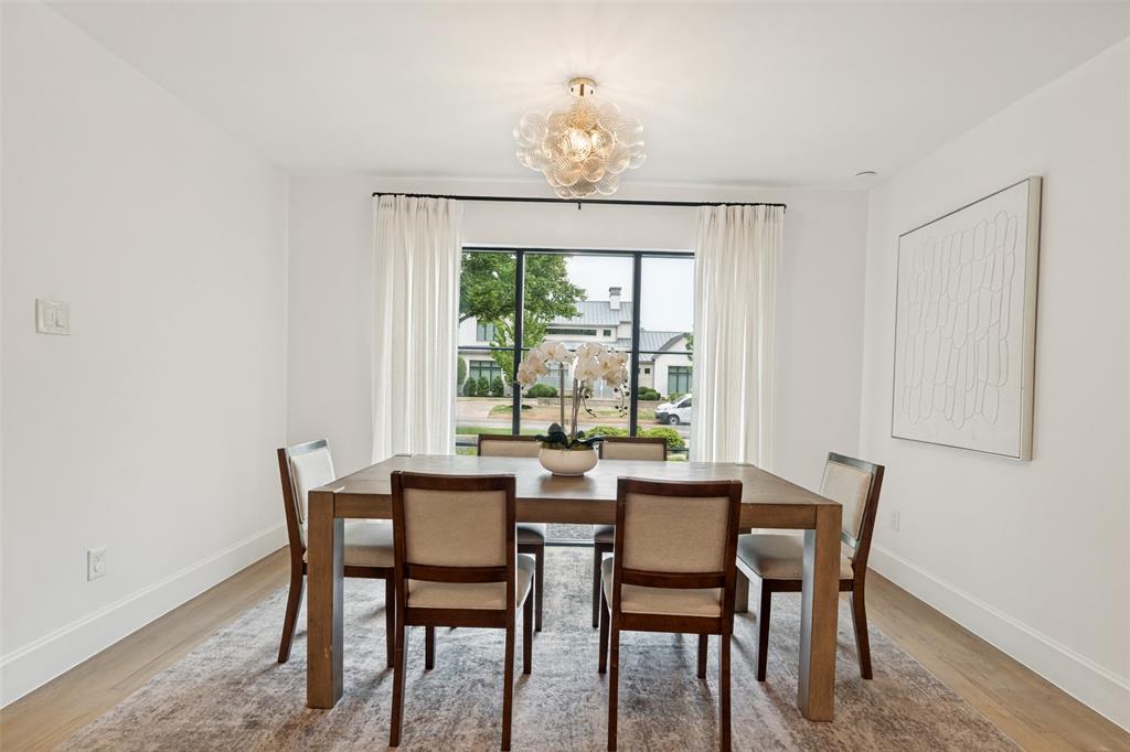 4325 Pomona Road Dallas, TX 75209 - Photo 12 of 23 Dining space featuring a large window with black framing and white drapery, wood-finish flooring, and white baseboards
