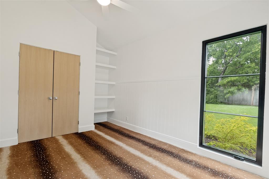 4325 Pomona Road Dallas, TX 75209 - Photo 13 of 23 Room featuring vaulted ceilings with a ceiling fan, a large window with black trim, built-in shelving, and wood-finish bifold closet doors