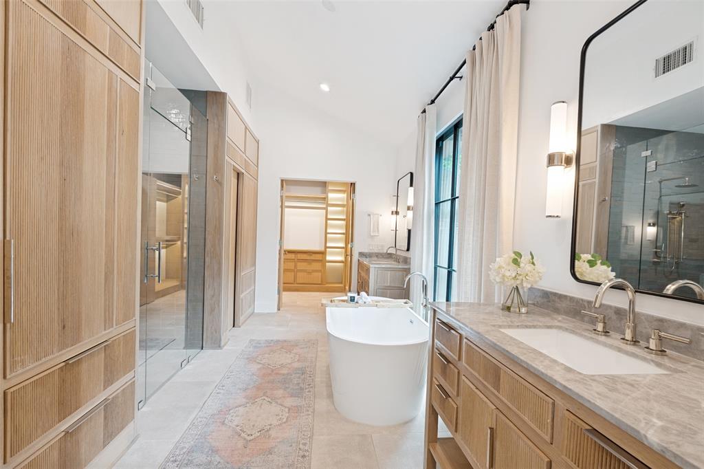 4325 Pomona Road Dallas, TX 75209 - Photo 15 of 23 Spacious bathroom featuring a freestanding soaking tub, dual vanity with stone countertops, and extensive built-in wood cabinetry