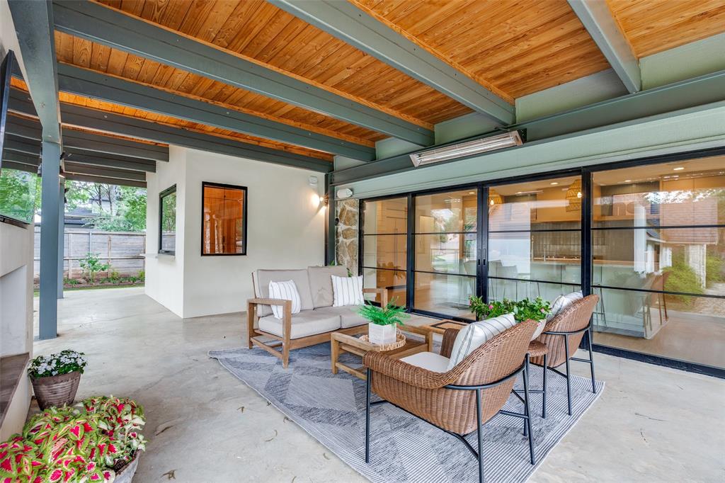4325 Pomona Road Dallas, TX 75209 - Photo 22 of 23 Expansive covered patio featuring a wood-panel ceiling with exposed beams, concrete flooring, and a stone accent wall