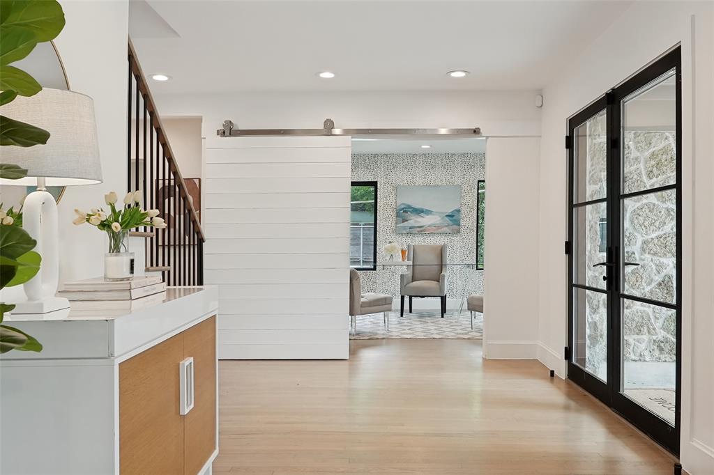 4325 Pomona Road Dallas, TX 75209 - Photo 3 of 23 Light wood-finish flooring throughout, featuring a white shiplap barn door, recessed lighting, and a contemporary staircase with dark wood handrails