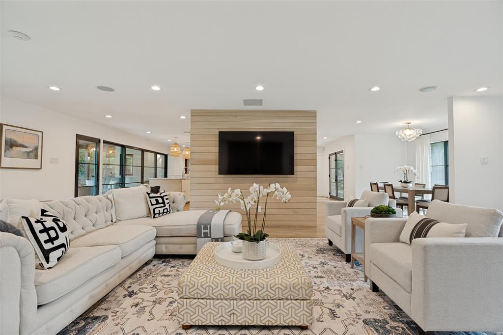 4325 Pomona Road Dallas, TX 75209 - Photo 5 of 23 Open-concept living area featuring a wood-panel accent wall with mounted television, recessed lighting, and expansive glass doors