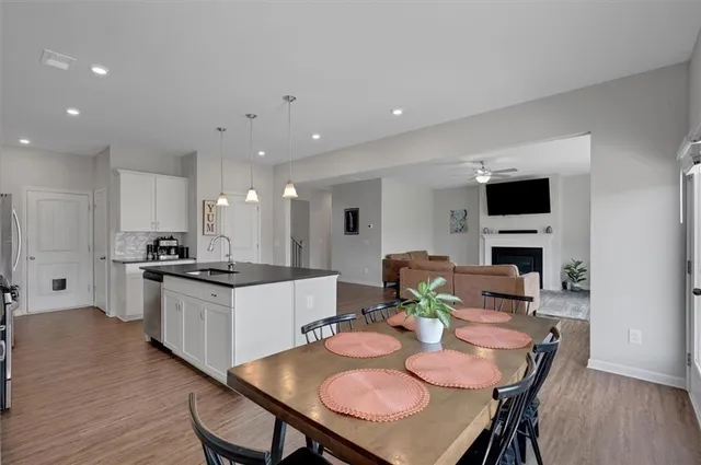 a kitchen with stainless steel appliances kitchen island granite countertop a stove a sink a dining table and chairs