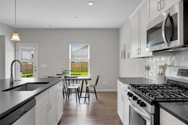 a kitchen with stainless steel appliances granite countertop a stove a sink and a microwave