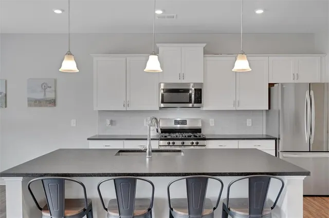 a kitchen with granite countertop a stove a refrigerator a sink a counter space and cabinets