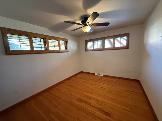 a view of empty room with wooden floor and fan