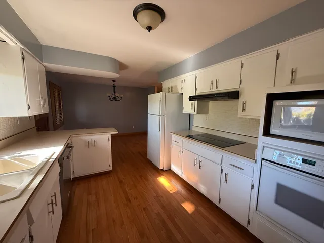 a kitchen with granite countertop a stove a sink dishwasher and a refrigerator with wooden floor
