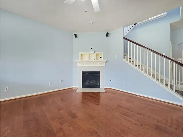a view of an empty room with a fireplace and a chandelier fan
