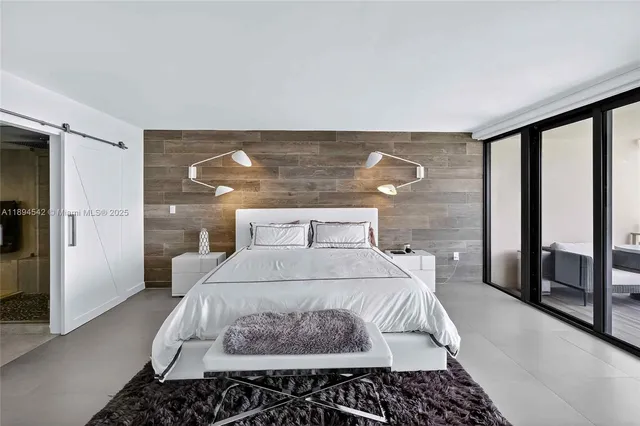 a bedroom with a bed and a flat tv screen on dresser