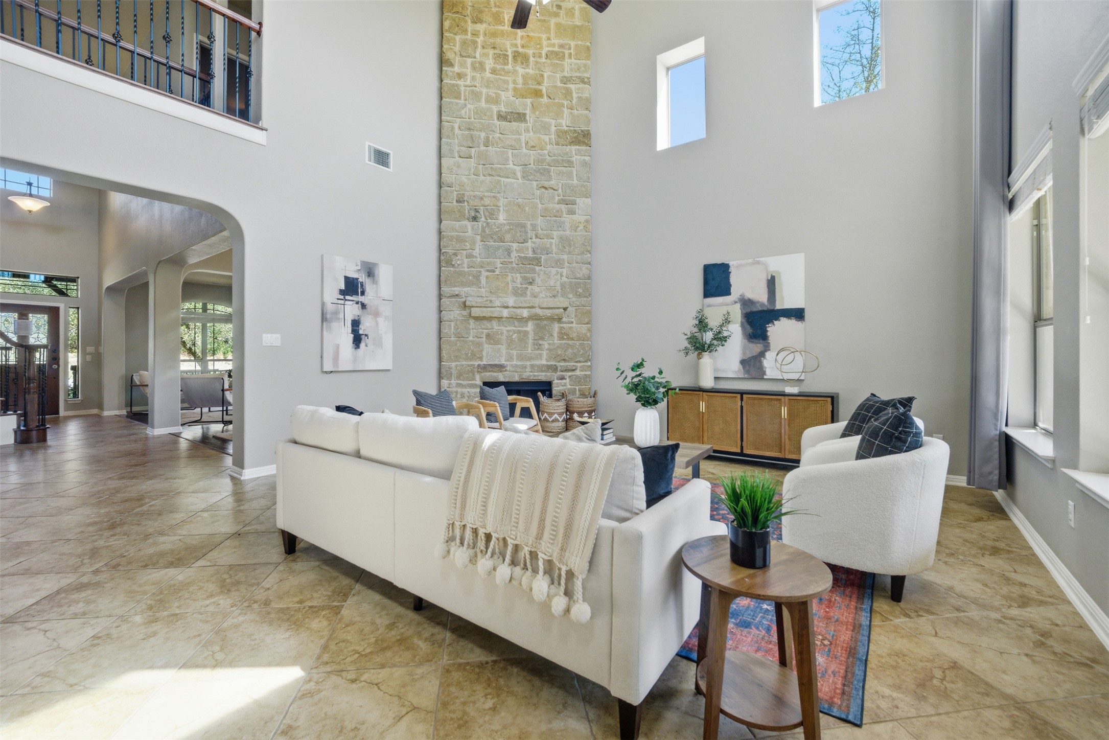 16100 Spillman Ranch Loop Austin, TX 78738 - Photo 11 of 39 Living room featuring arched walkways, plenty of natural light, a fireplace, a high ceiling, and ceiling fan