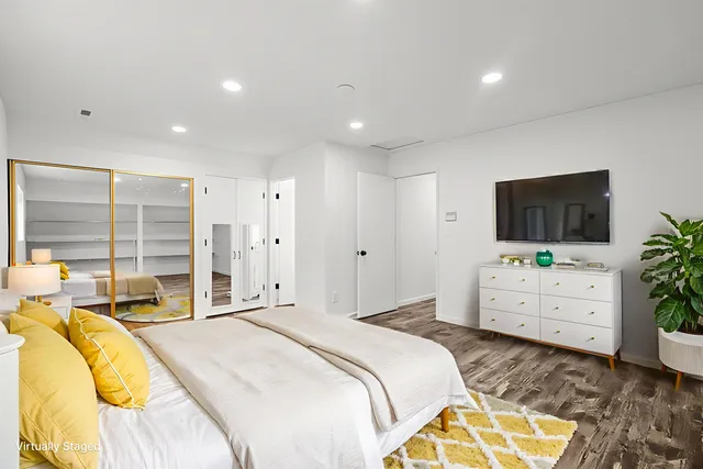 a spacious bedroom with a bed and a flat screen tv