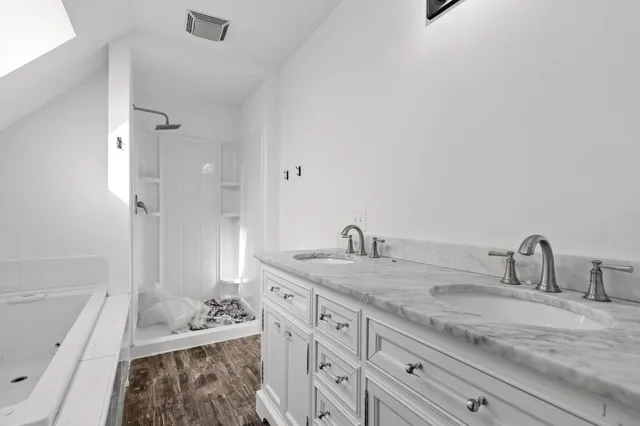 a bathroom with a sink double vanity granite tub shower and a mirror