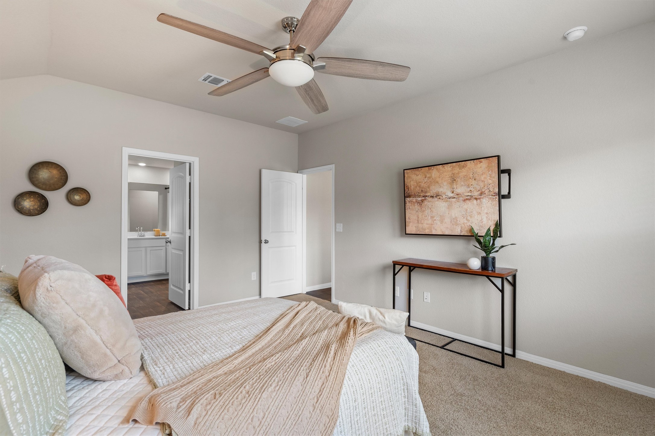 19525 Abigail Fillmore Road Manor, TX 78653 - Photo 14 of 38 Plush carpeting and a tasteful ceiling fan define comfort in this primary bedroom suite, with an adjoining private bathroom visible.