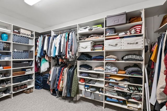 a view of walk in closet with clothes and shoes