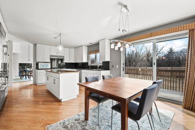 a kitchen with stainless steel appliances granite countertop a table chairs sink and cabinets