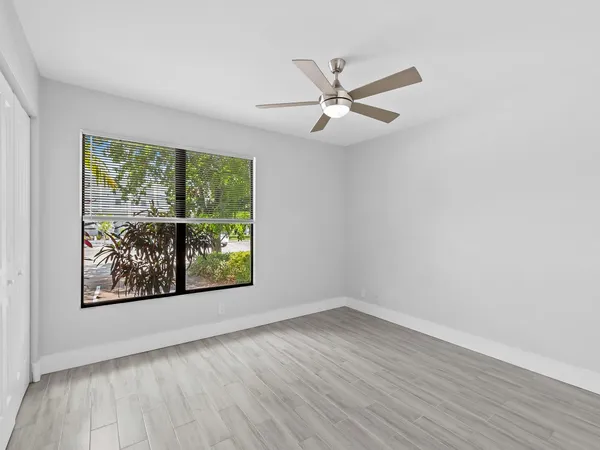 an empty room with wooden floor and ceiling fan