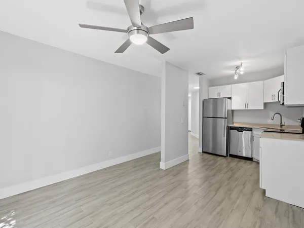 an empty room with wooden floor fan and windows