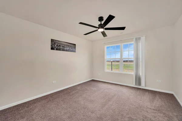 a view of a big room with wooden floor a ceiling fan and windows